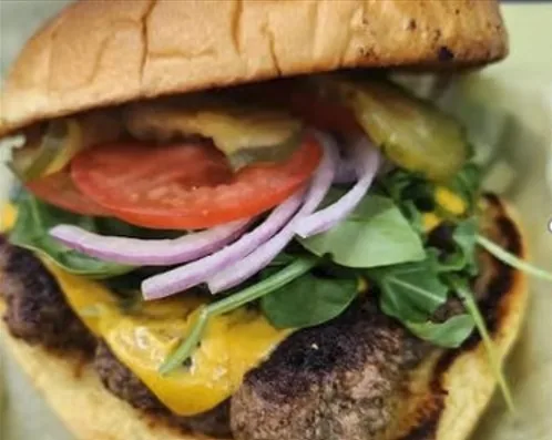 A Flavor on 51 burger with cheese, tomato, onion and greens